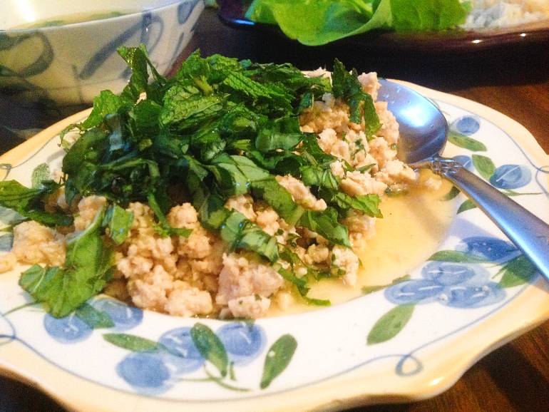 Chicken larb topped with fresh mint, cilantro, and basil leaves.