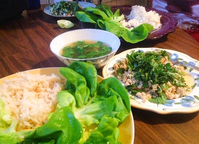 Chicken larb on lettuce leaves with rice and broth.