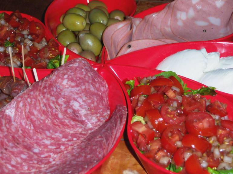 Deli appetizer of salami, mortadella, prescuitto-wrapped smoked oysters, fresh mozerella, garlic-stuffed olives, and caprese salad.